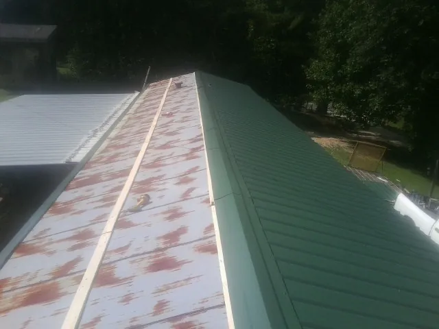 Old rusted panels beside newly installed green metal roofing — Wind Damage Roof Repair by Roofing Brothers in Sheboygan