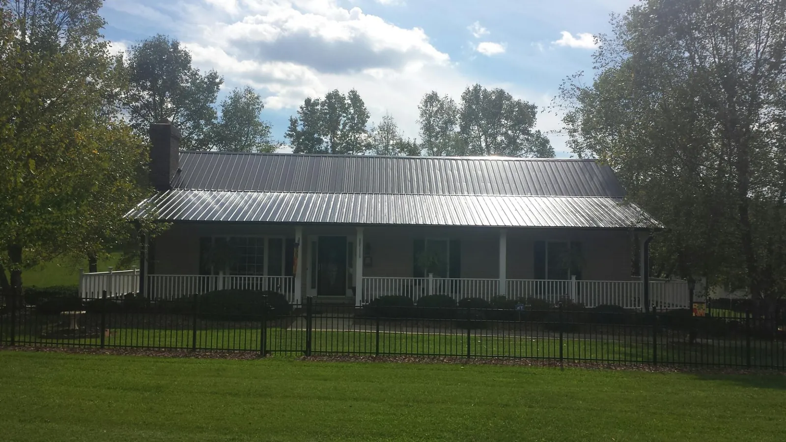 Gray metal roof on a brick ranch with a full width front porch — Gutter Guard Installation work by our crew in Sheboygan