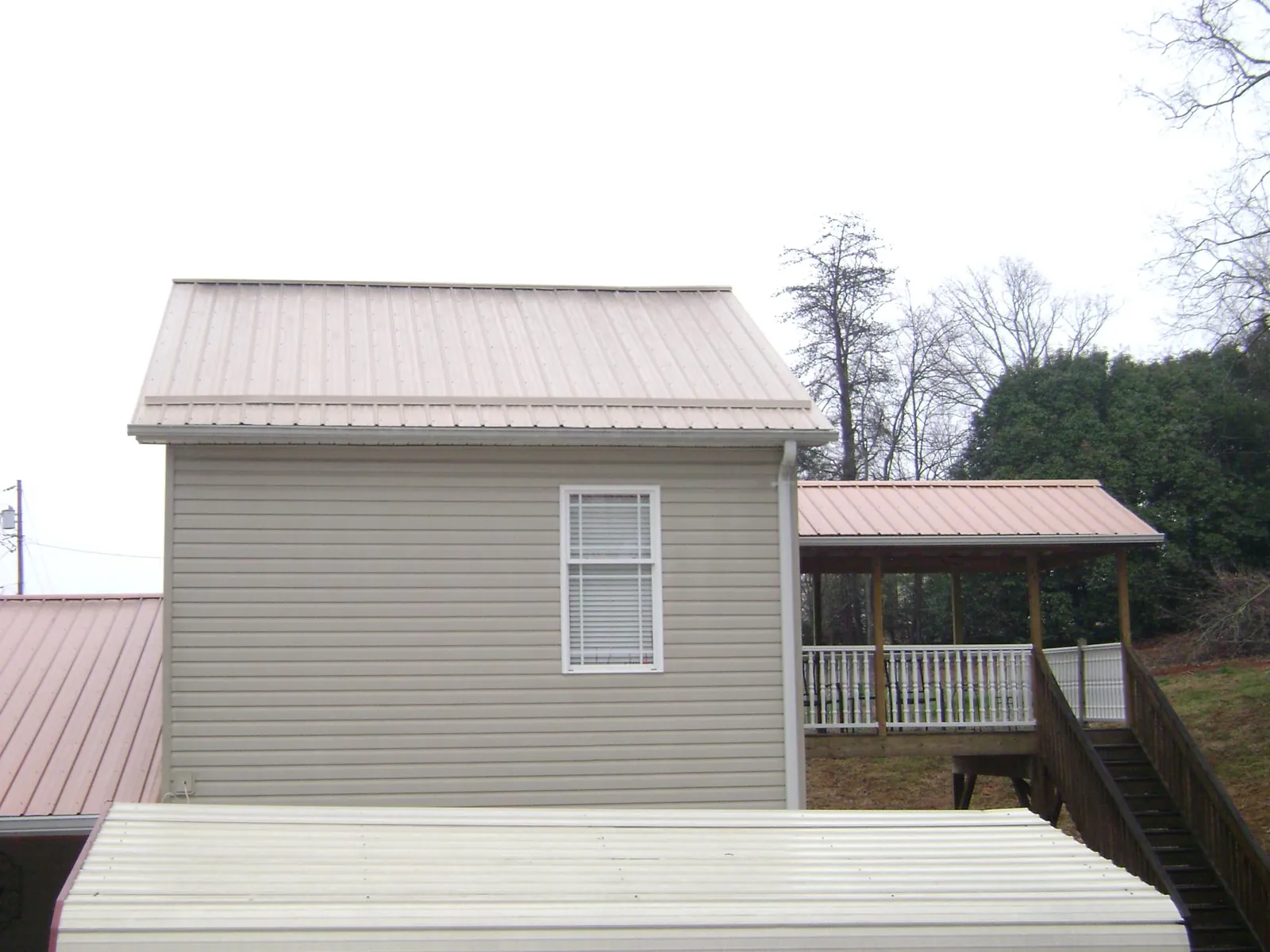 Tan metal roofs on a two story addition and attached porch, from a Roof Replacement job in Sheboygan
